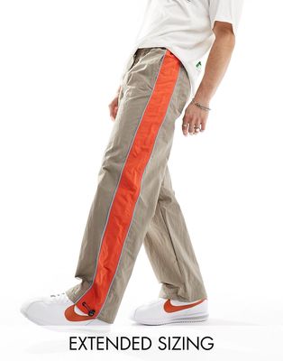 ASOS DESIGN baggy nylon track pants in brown with orange side stripe