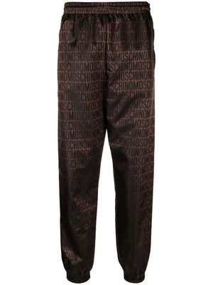 Moschino all-over logo-print trousers - Brown